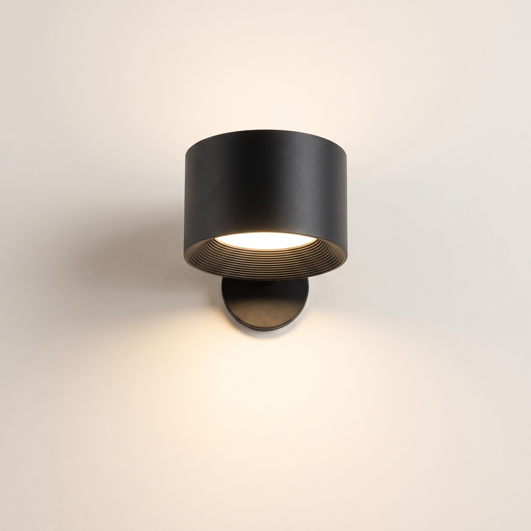 Black cordless wall lamp, 7.5 cm, switched on, on a warm off-white background